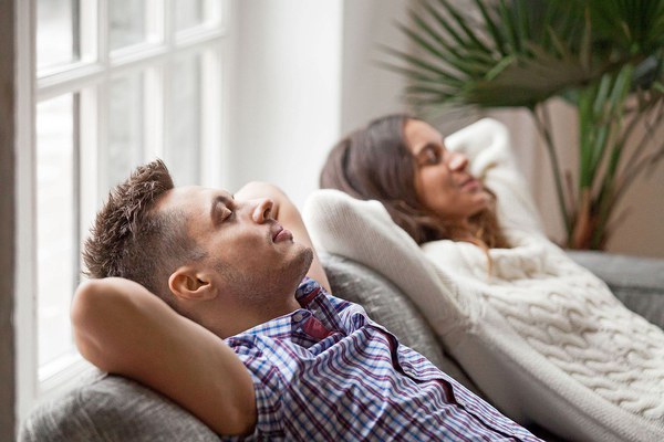 Young couple resting on comfortable couch together at home, happy man and woman enjoying relaxation or nap dozing on sofa with eyes closed, calm family breathing fresh air feeling totally relaxed