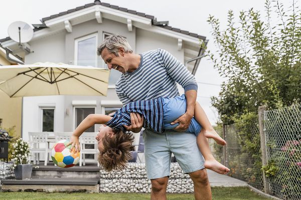 Playful father and son with football in garden
