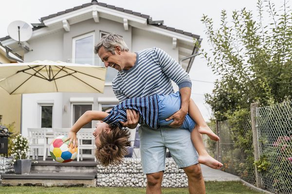 Playful father and son with football in garden Playful father and son with football in garden
